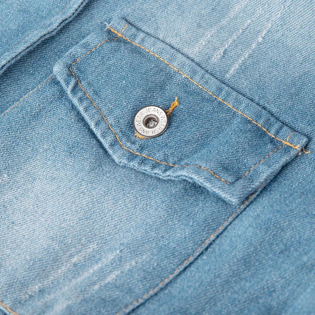 Close-up of a denim fabric with a pocket and button detail, highlighting the texture and stitching.