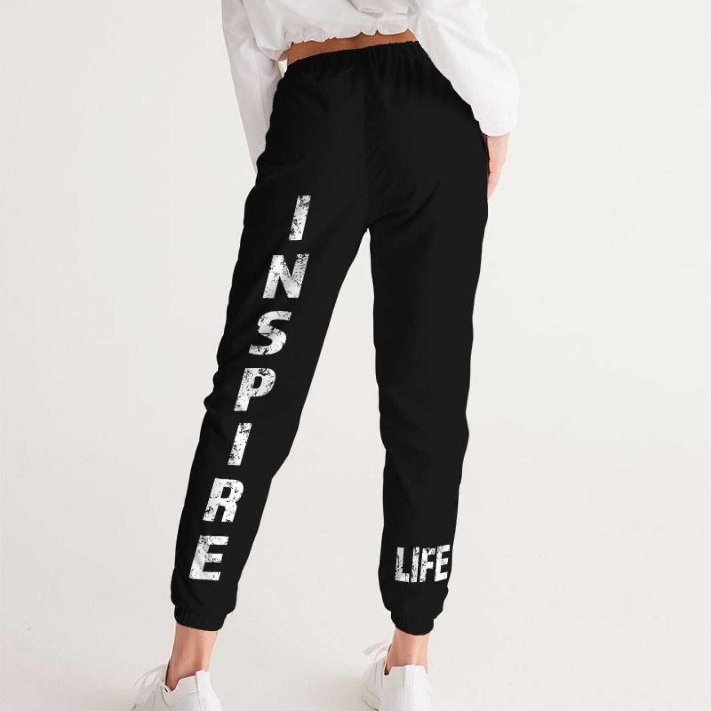 Women's black track pants with "Inspire" graphic, water-resistant, elastic waistband, zip pockets, perfect for exercise or casual wear.